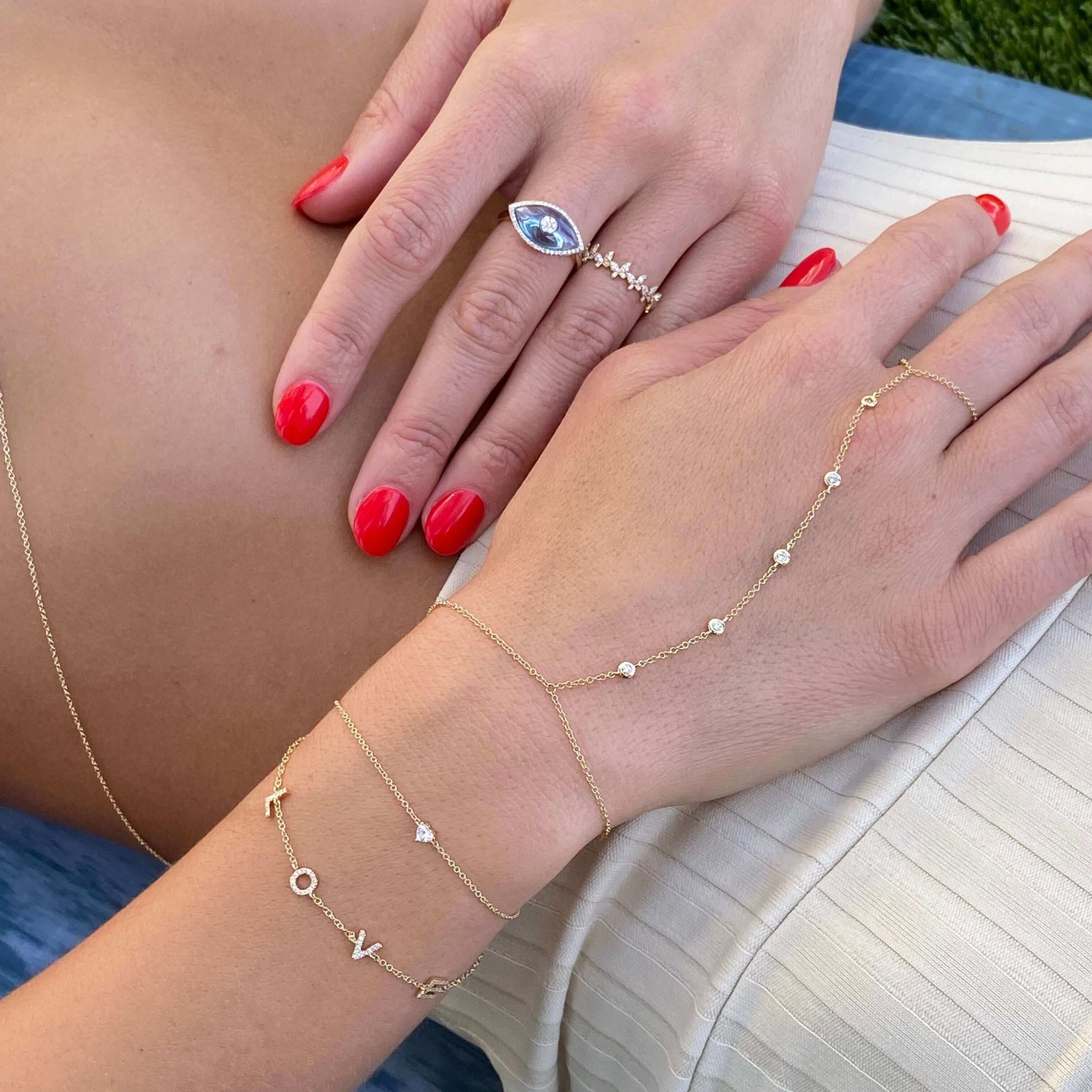 Elegant hand jewelry featuring gold chains with delicate diamonds and a blue gemstone ring from our jewelry brand.