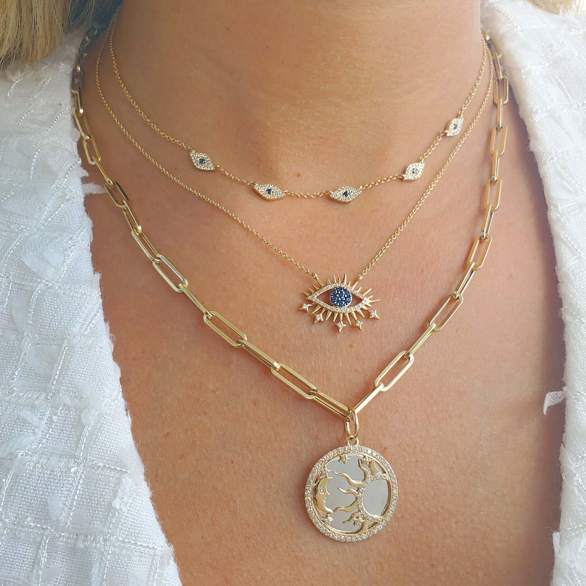 Layered gold necklaces with eye and tree pendants designed by our luxury jewelry brand.