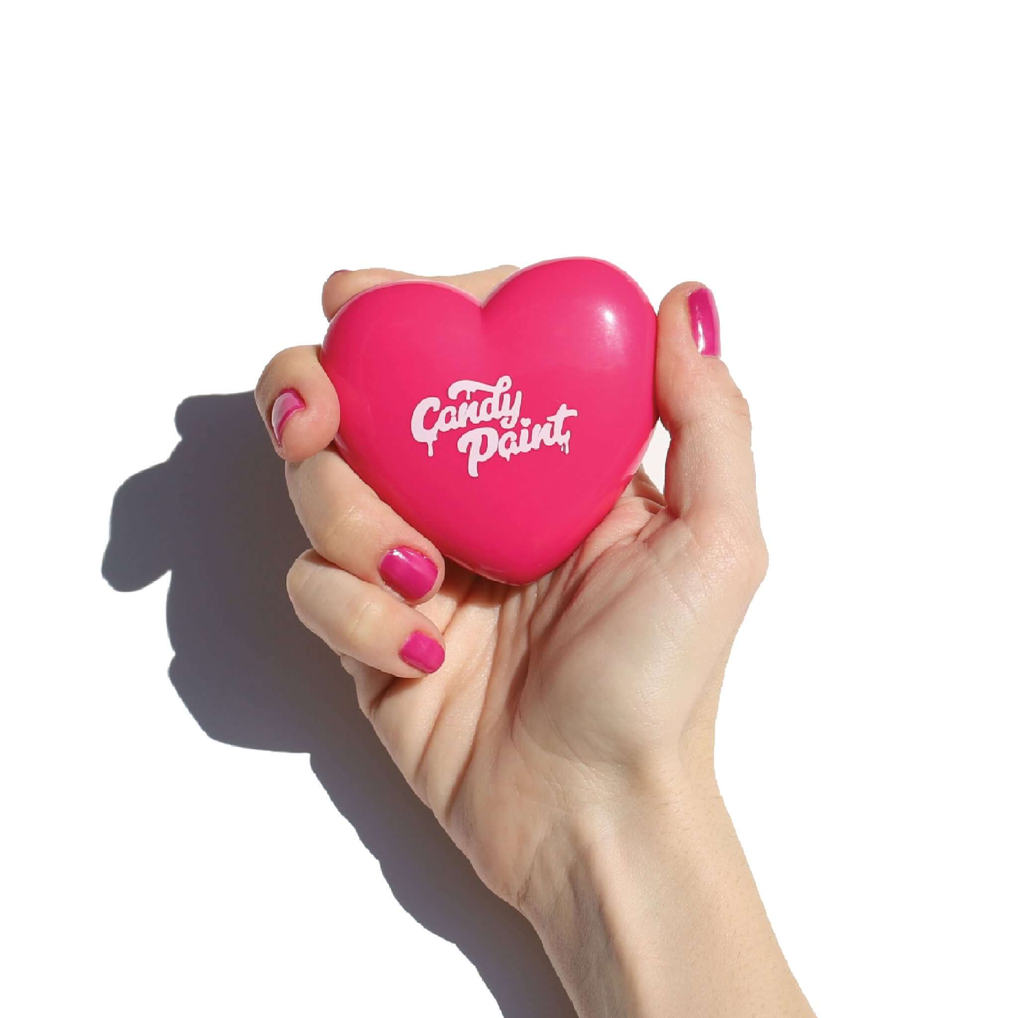A hand holding a heart-shaped compact of Candy Paint Cream Highlighter.