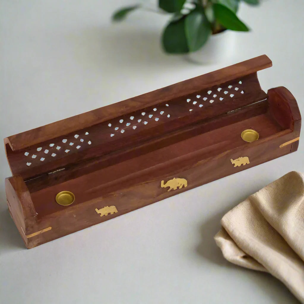 A wooden incense burner with perforations and an elephant design, featuring gold accents.