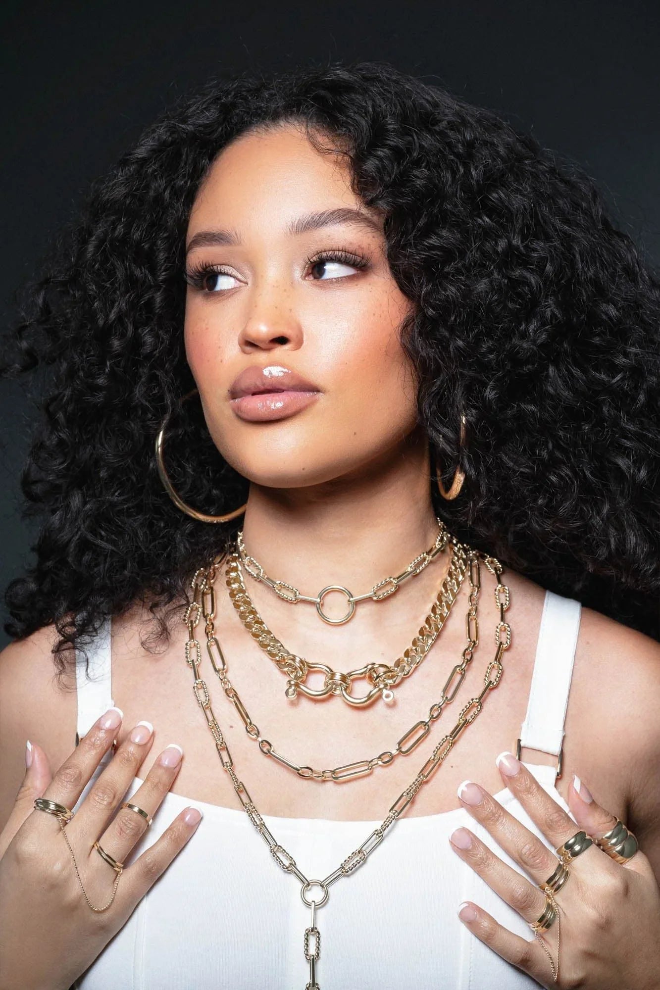 Woman showing off stylish gold necklaces and rings with the Dean Necklace product
