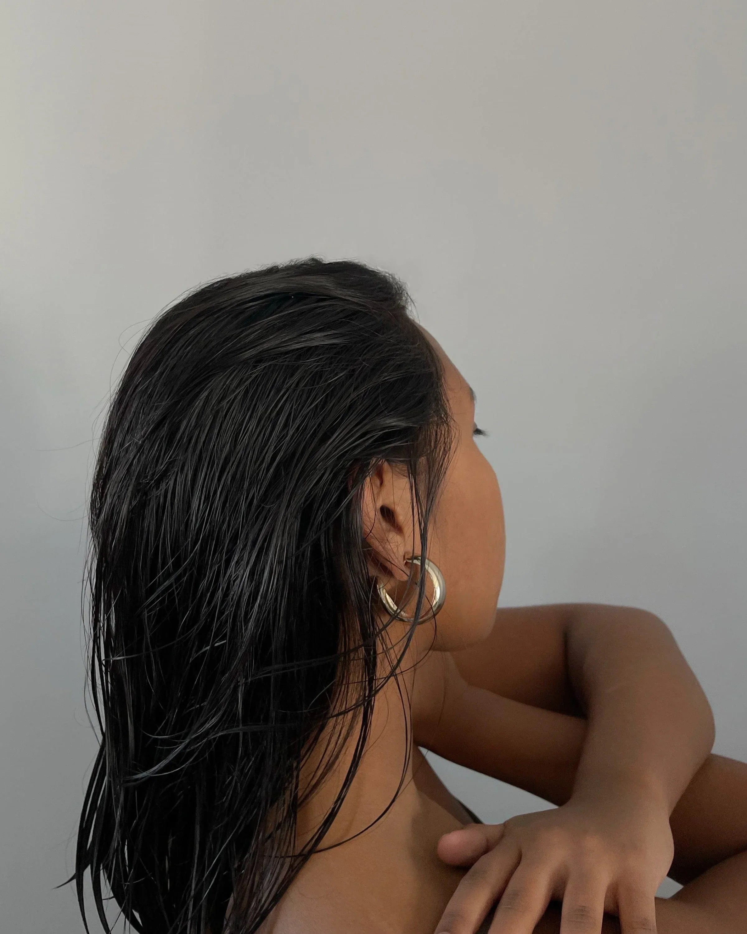 Woman with wet hair and hoop earrings wearing Simone Hoops jewelry