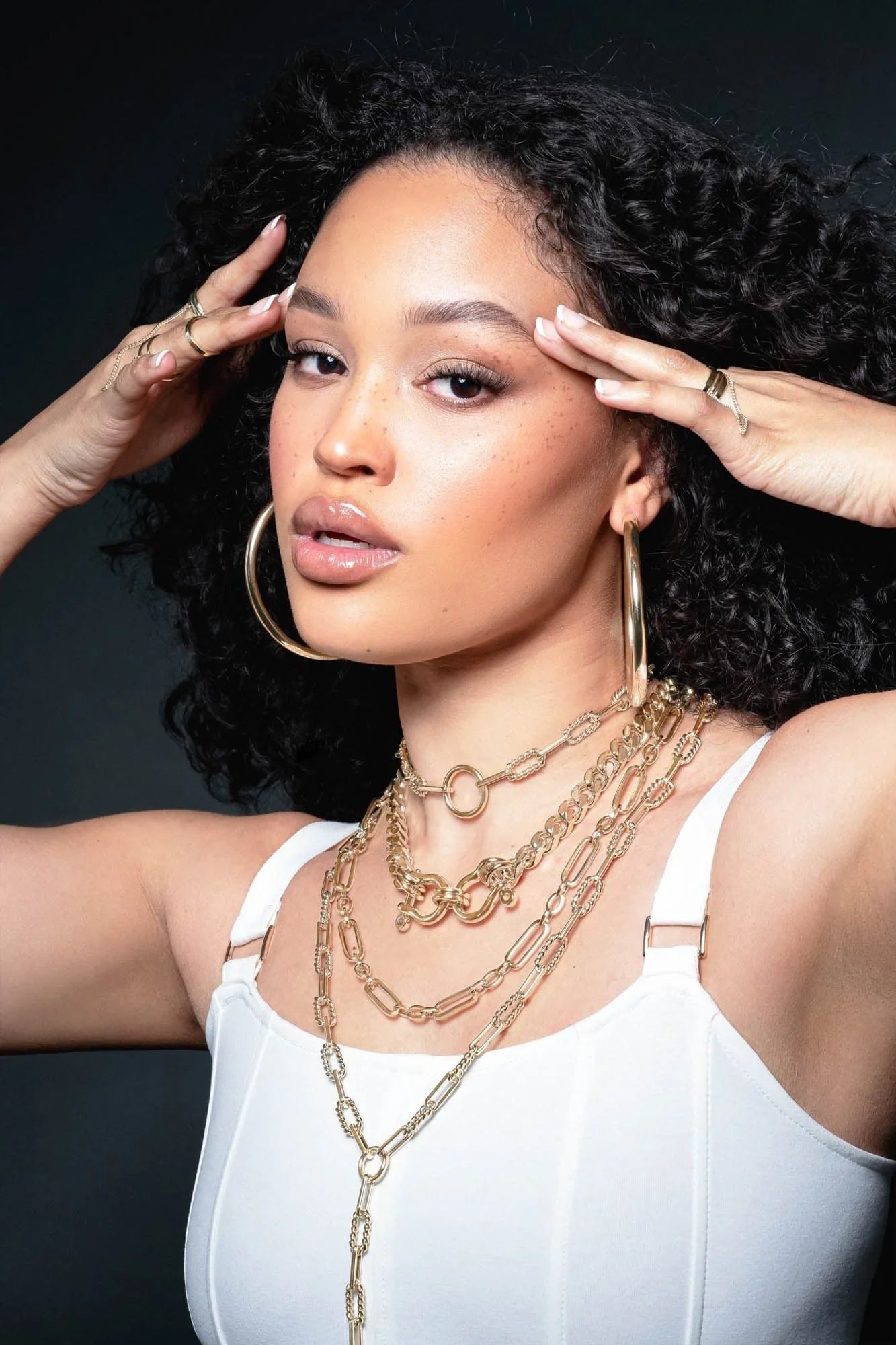 Woman wearing gold jewelry showcasing the Skye Necklace style and elegance