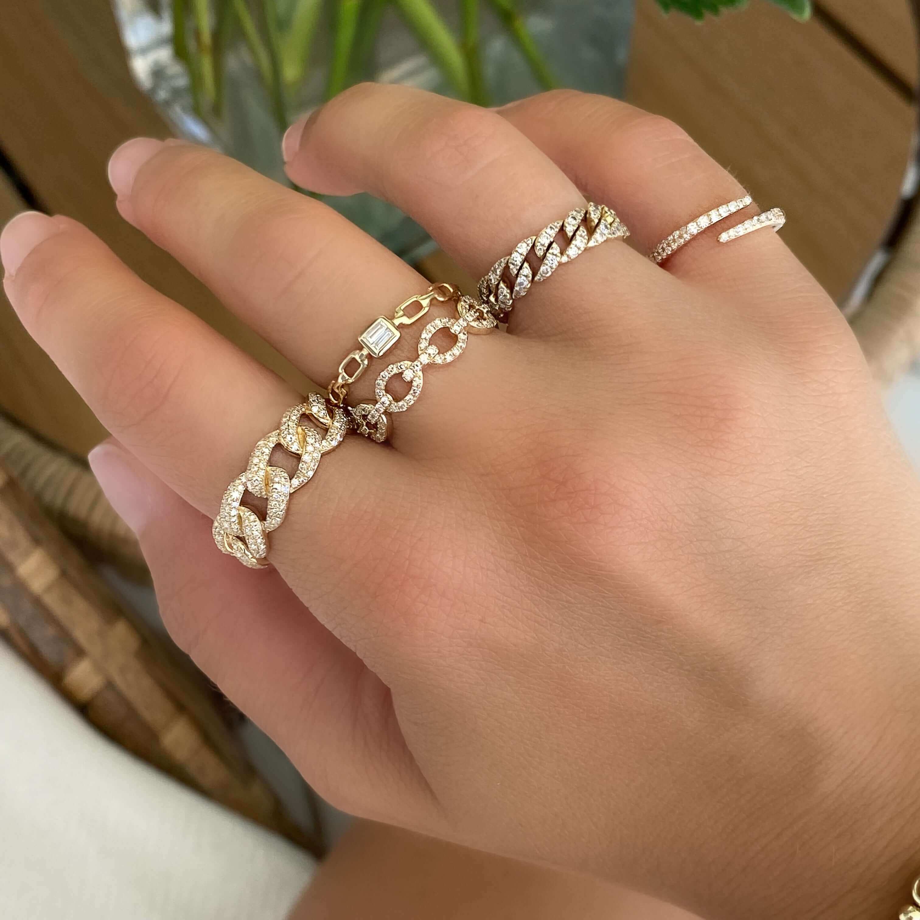 Elegant gold rings with intricate designs and gemstones on a hand, showcasing luxury jewelry from our exclusive collection.