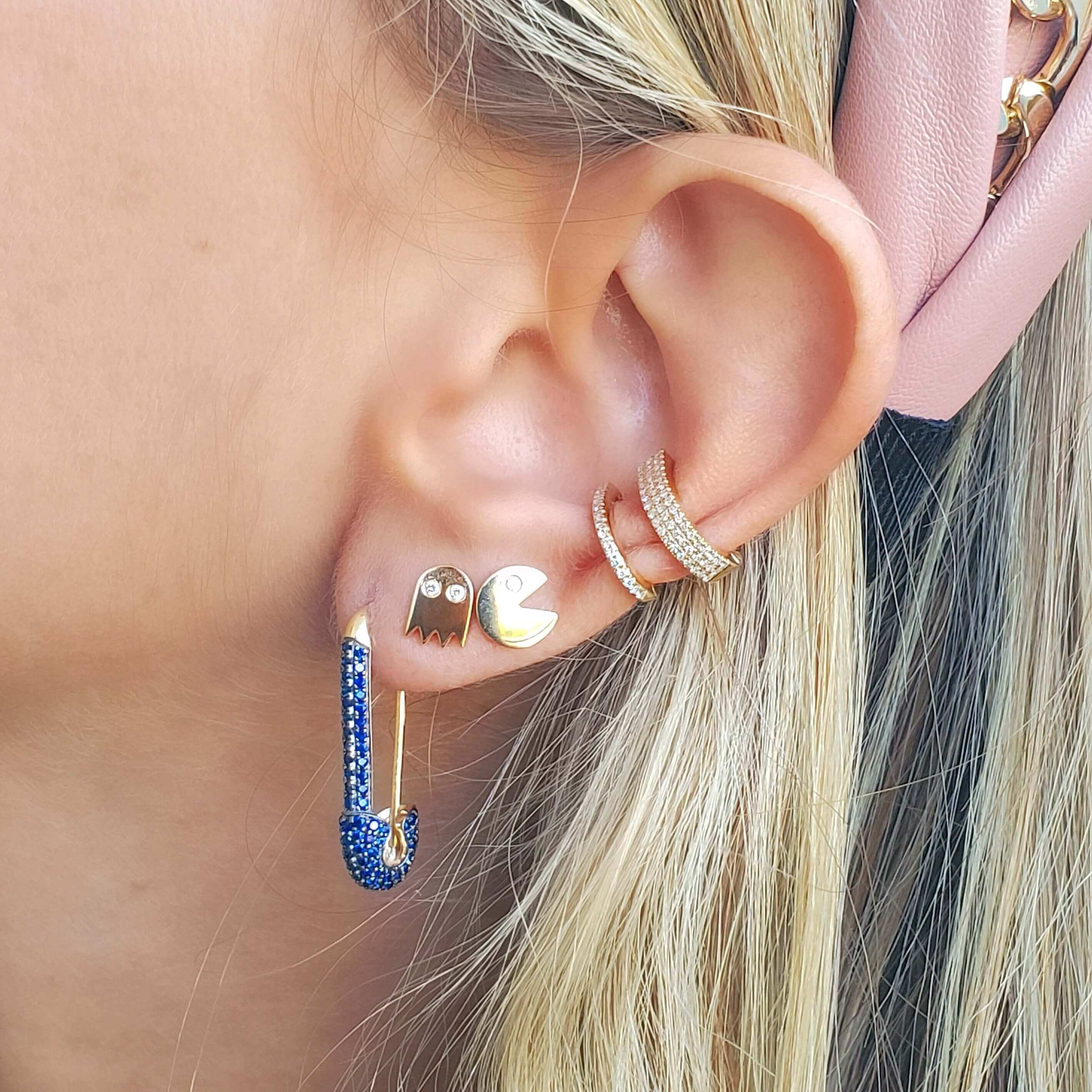 Woman wearing trendy gold Pac-Man earrings and blue safety pin earring from our jewelry collection, perfect for a unique and stylish look