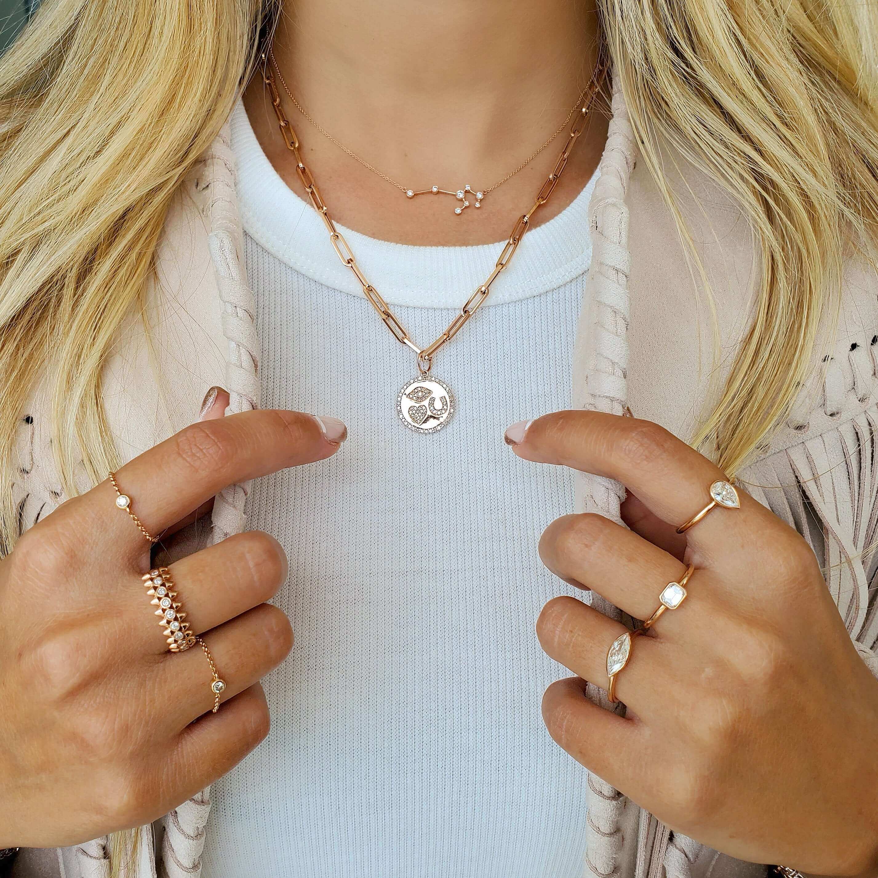 Woman showcasing layered gold necklaces and stylish rings from our jewelry brand.