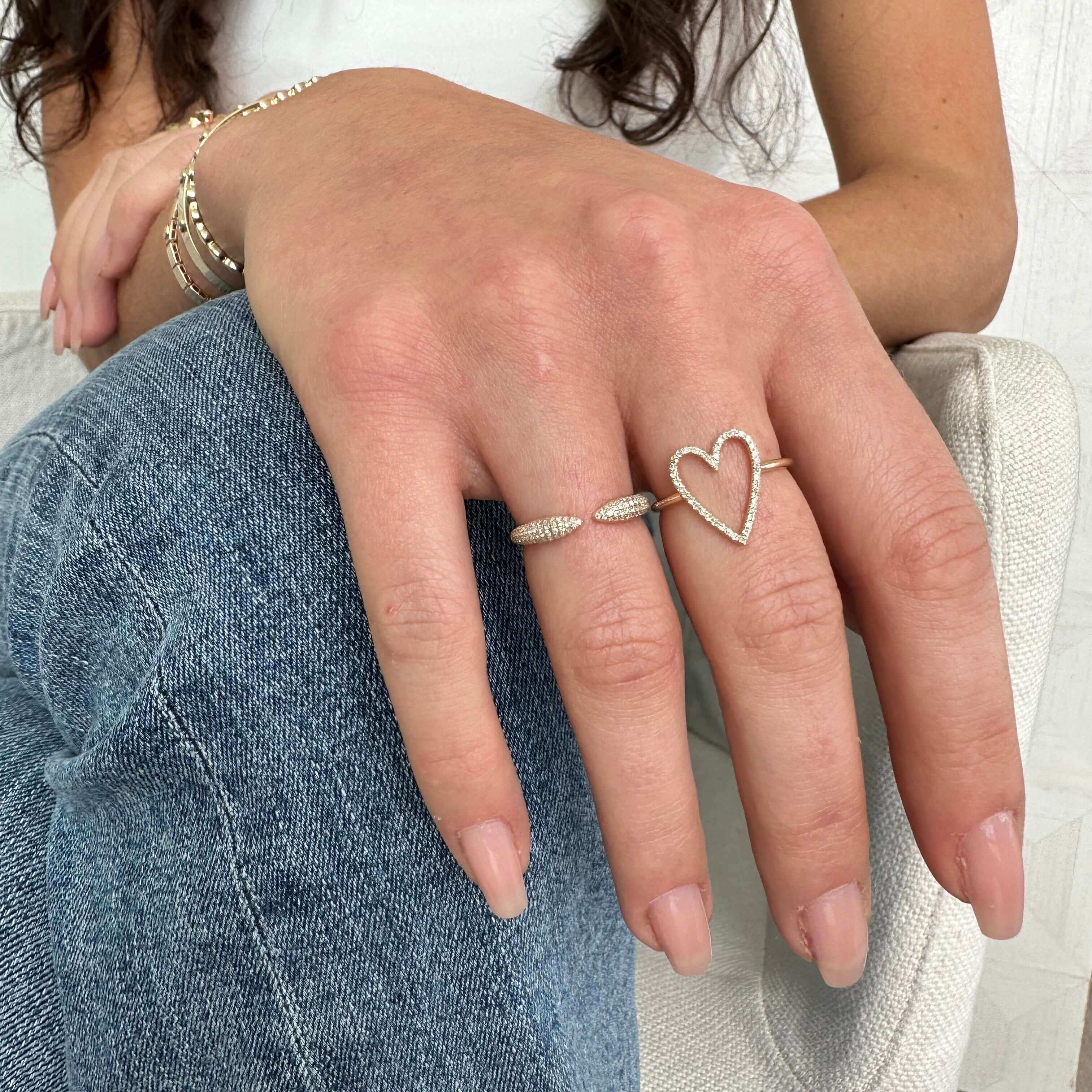 Woman's hand adorned with stylish gold bracelets and a heart-shaped ring from our exquisite jewelry collection.