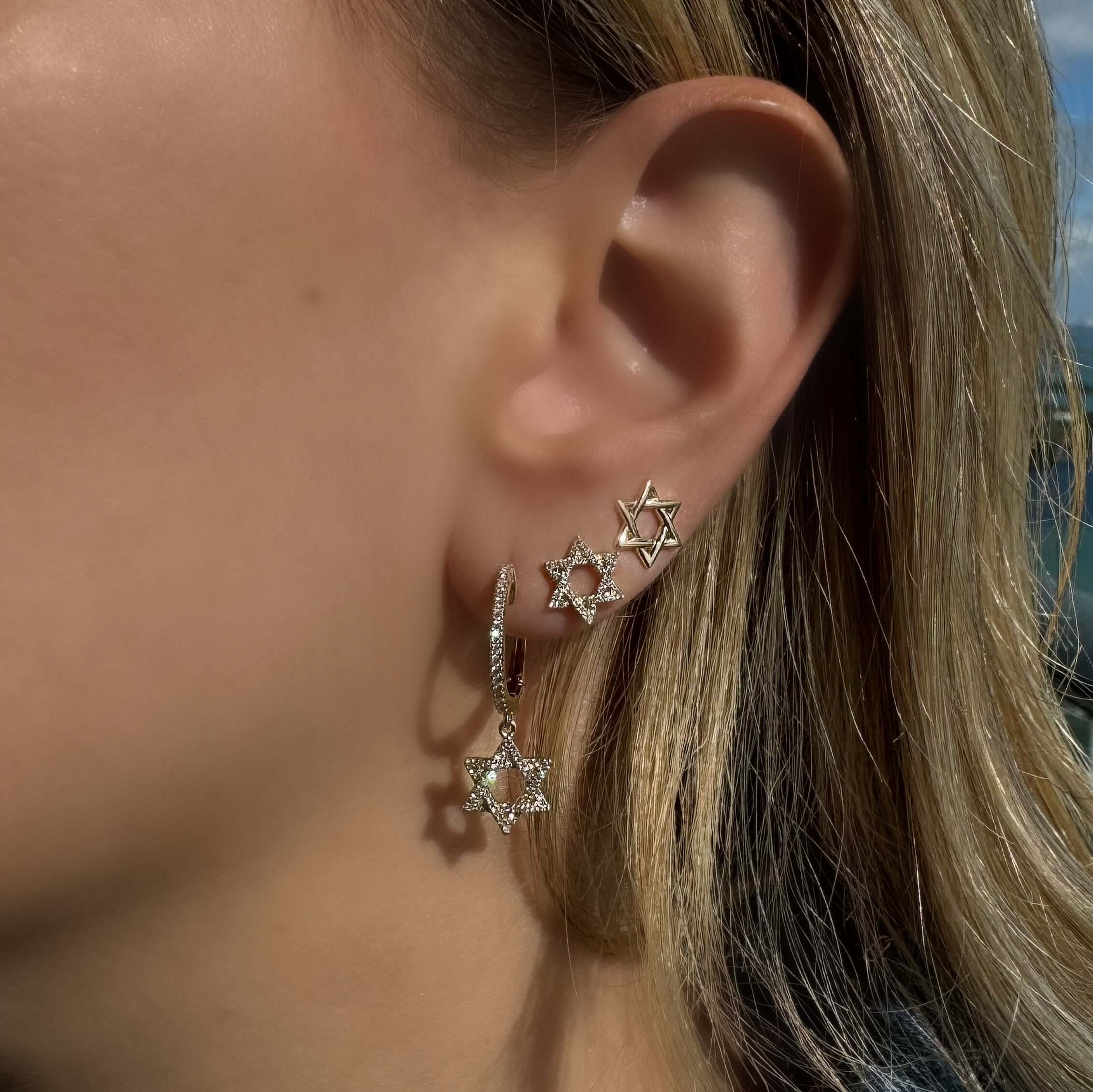 14K gold small Star of David earrings worn on earlobe, showcasing elegant design and sparkling details.