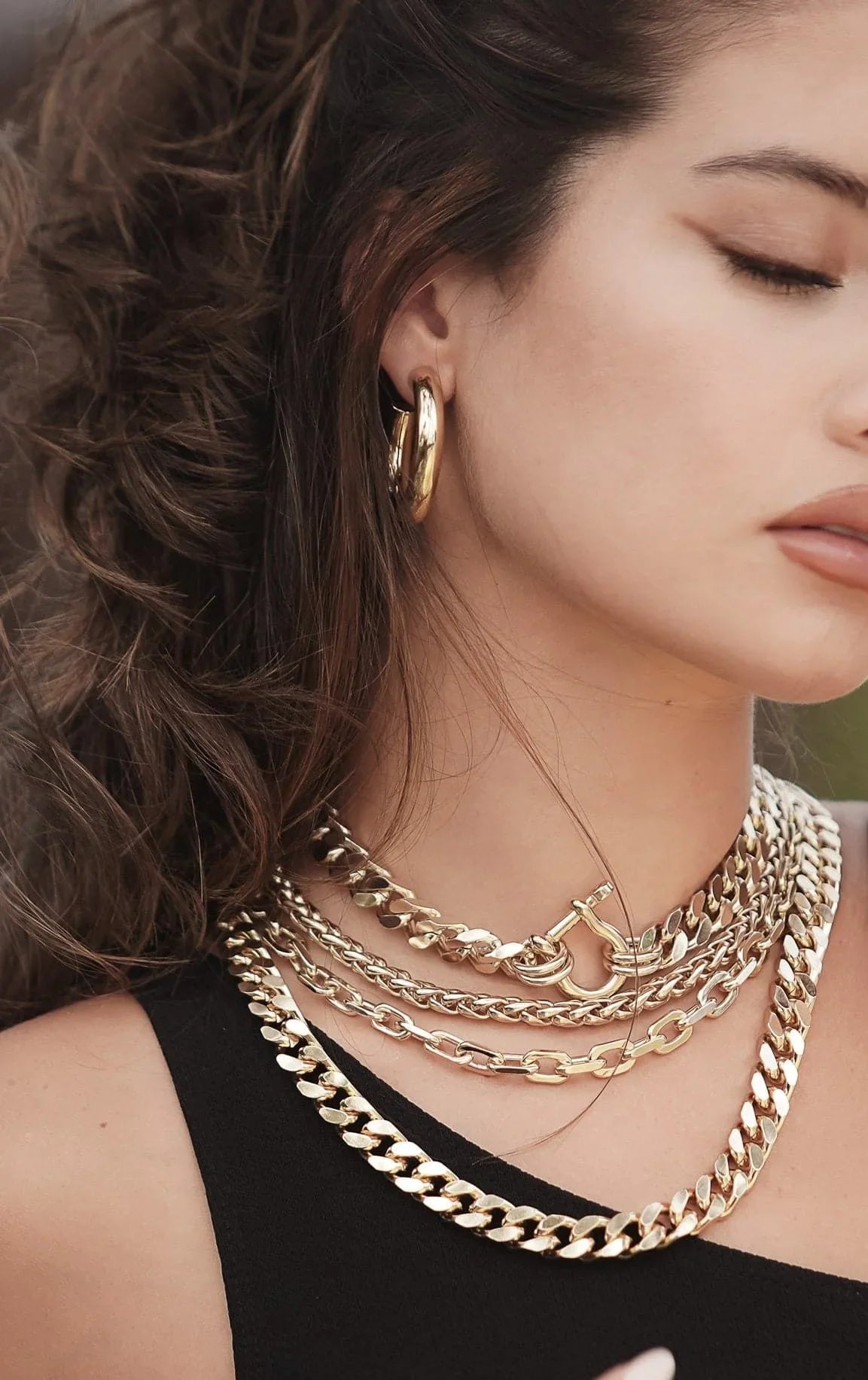 Woman wearing elegant gold jewelry showcasing the Esmé Necklace in this stylish shot