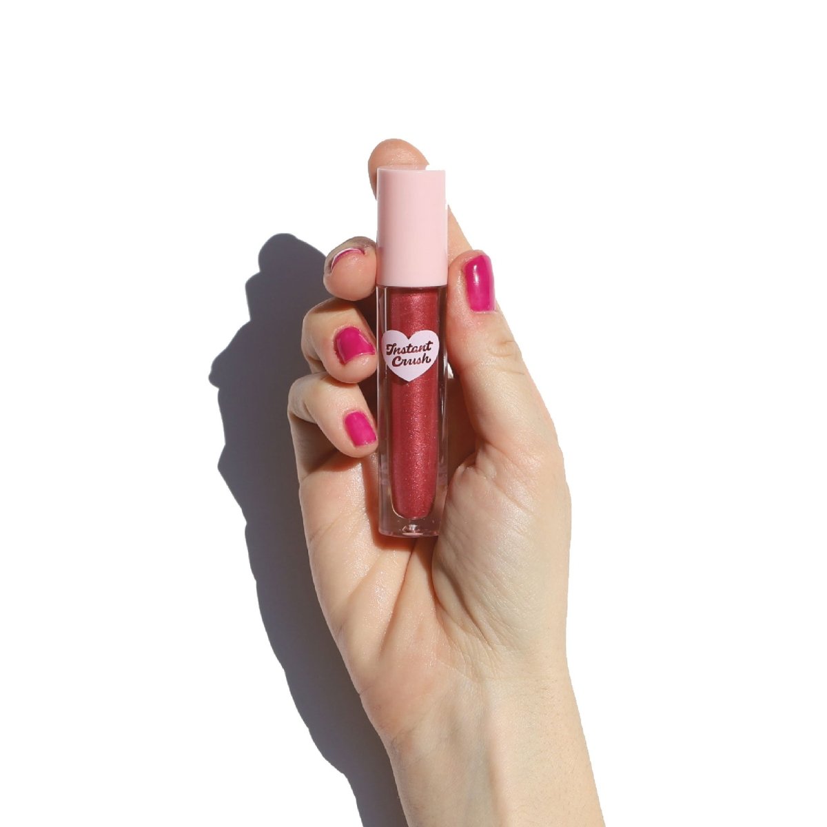 Hand with pink nail polish holding lip gloss - Instant Crush - Caught Up - Half Caked